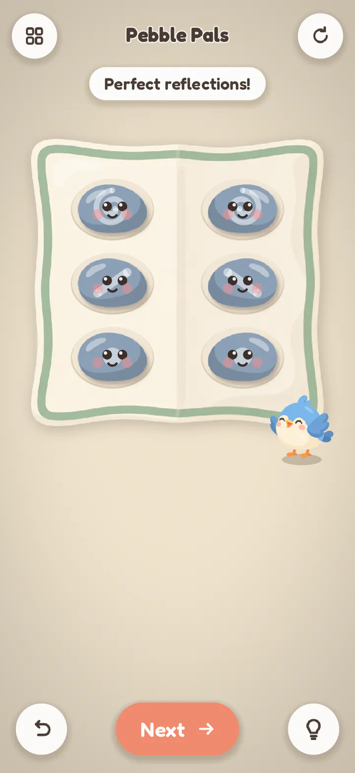 Pebble Pals finished: twin pebbles facing each other across a folded cloth, now with smiling faces.